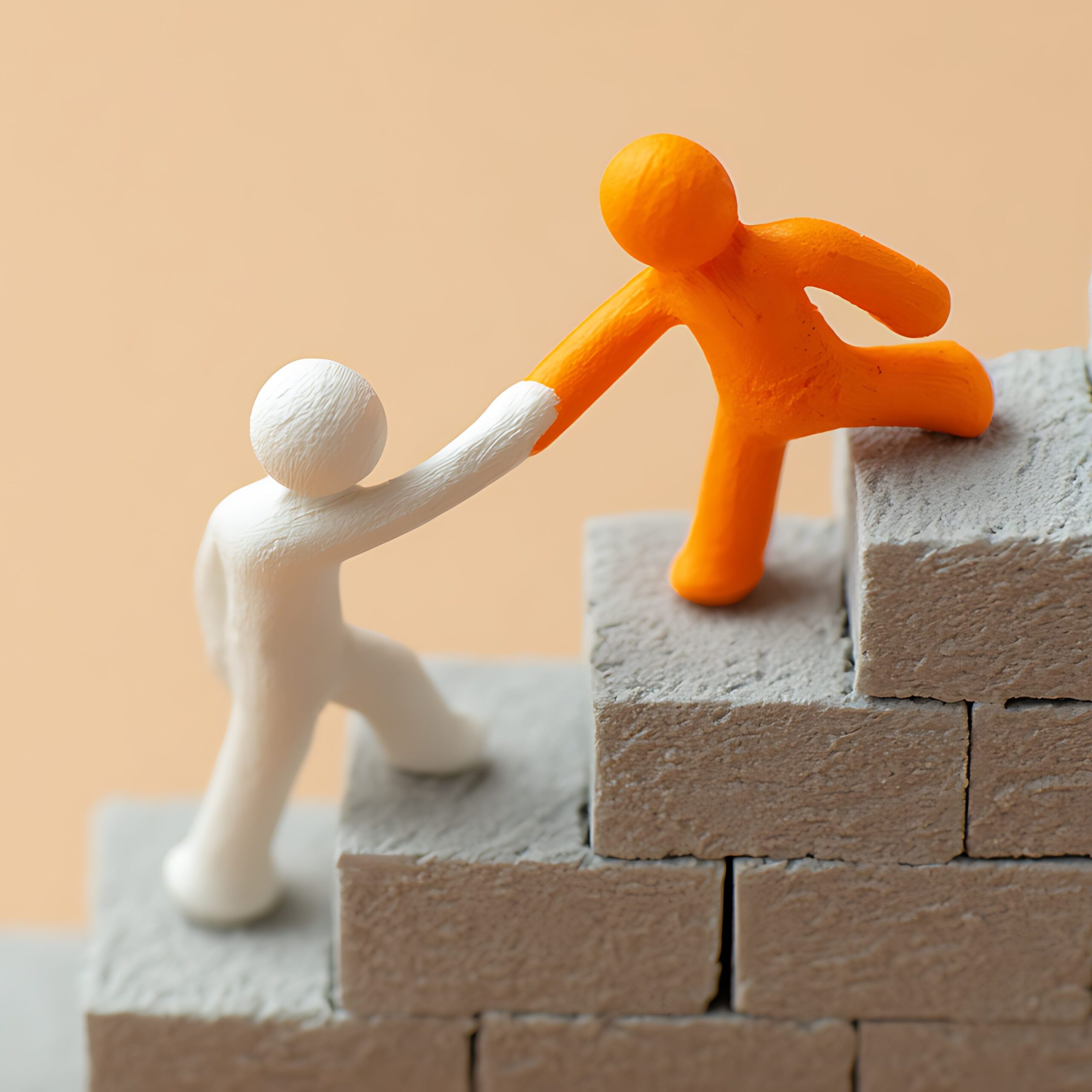 Two 'stickmen' standing on bricks, one helping the other up the steps.