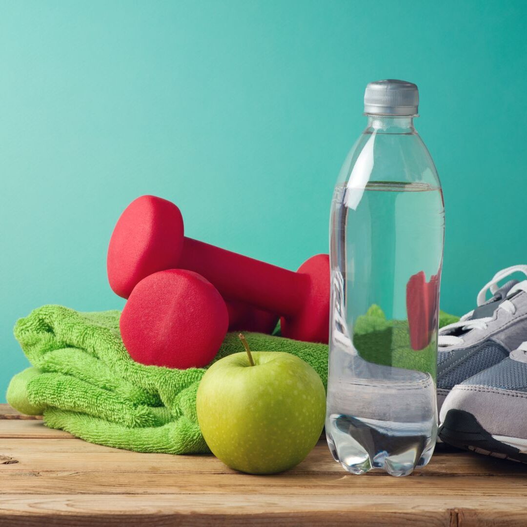 Workout materials on bench - including apple, water bottle, towel, barbells and tennis shoes 